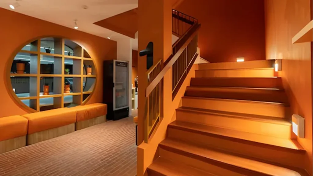 Orange-toned Monkey Market shared area with seating and a staircase at Blu Monkey Hub & Hotel Bangsaen
