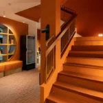 Orange-toned Monkey Market shared area with seating and a staircase at Blu Monkey Hub & Hotel Bangsaen