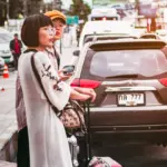 Travellers preparing luggage beside a parked car in Thailand